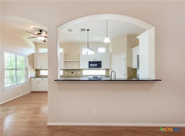 1935 Grandview Dr, Salado, TX 76571 - kitchen featuring black microwave, arched walkways, open shelves, dark countertops, and decorative backsplash