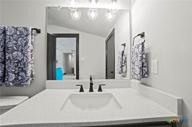 bathroom with vanity, toilet, and lofted ceiling