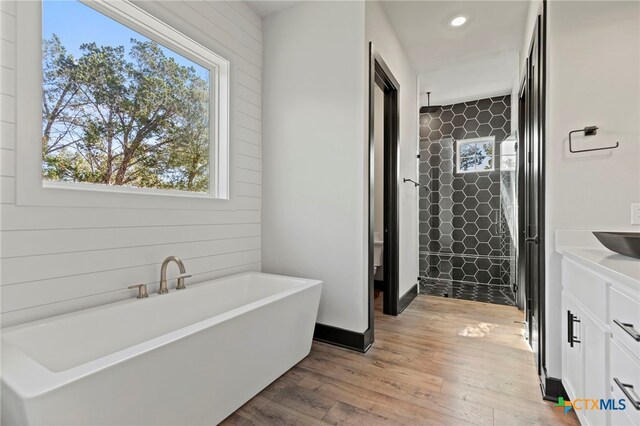 bathroom featuring hardwood / wood-style flooring, vanity, and shower with separate bathtub