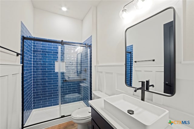 bathroom featuring walk in shower, hardwood / wood-style floors, vanity, and toilet