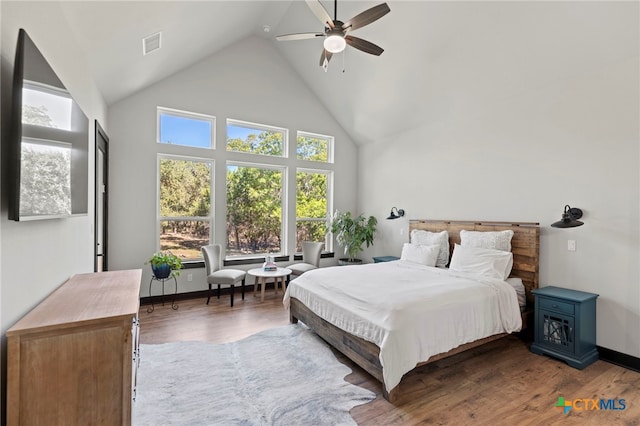 bedroom with hardwood / wood-style floors, high vaulted ceiling, and multiple windows