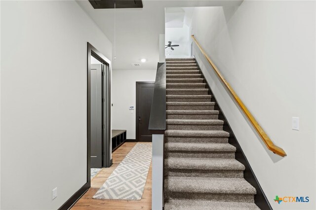 stairs featuring hardwood / wood-style flooring and ceiling fan