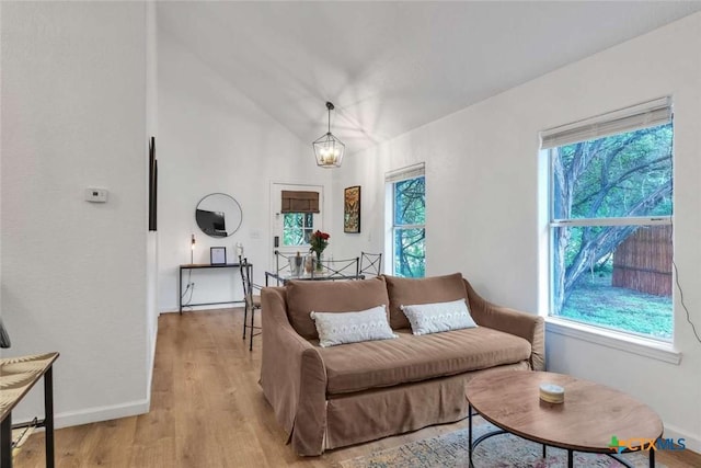 living room with baseboards, lofted ceiling, light wood-style floors, and a healthy amount of sunlight