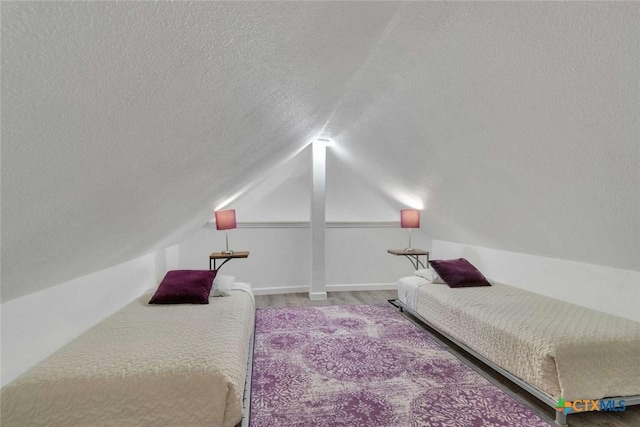 bedroom featuring vaulted ceiling, wood finished floors, baseboards, and a textured ceiling