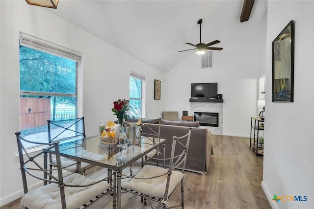 dining room with baseboards, lofted ceiling, wood finished floors, and a high end fireplace