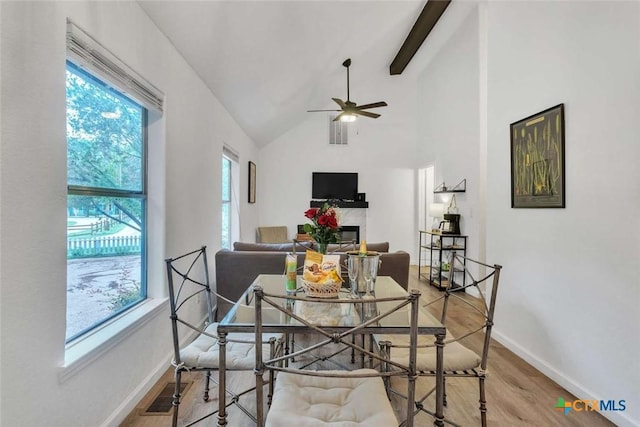 dining area featuring visible vents, beam ceiling, a glass covered fireplace, wood finished floors, and baseboards