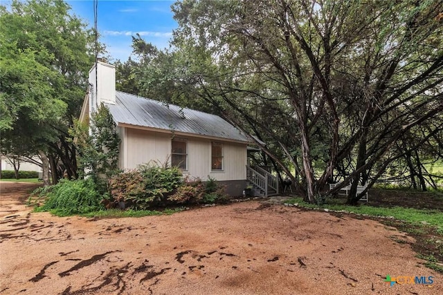 view of property exterior with a chimney and metal roof