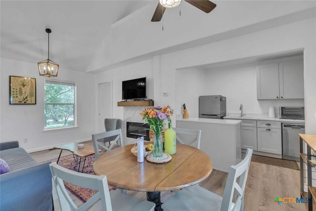 dining area with baseboards, lofted ceiling, ceiling fan, and light wood finished floors