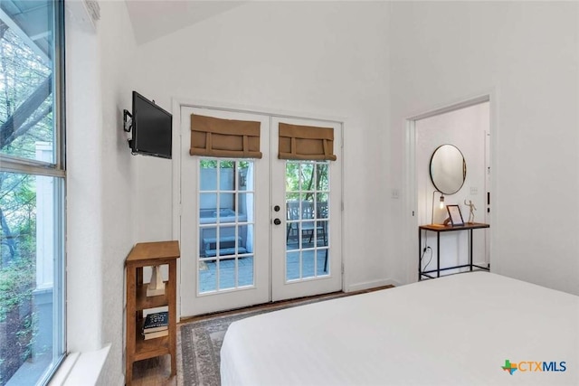 bedroom featuring wood finished floors, french doors, lofted ceiling, and access to exterior