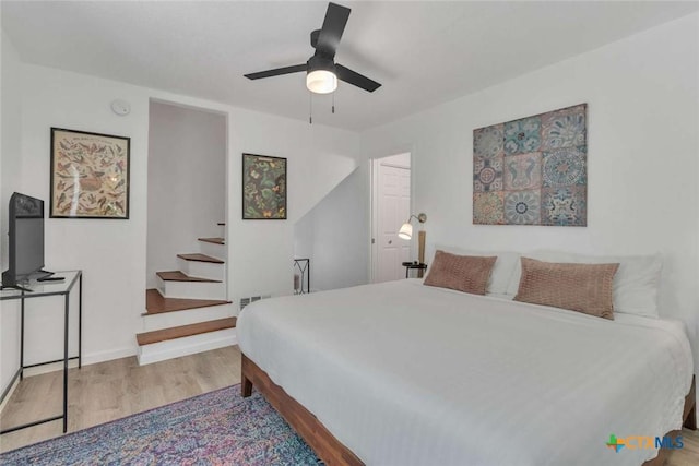 bedroom featuring ceiling fan, wood finished floors, visible vents, and baseboards