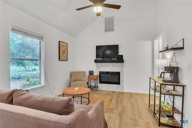 living room featuring wood finished floors, visible vents, a high end fireplace, and a healthy amount of sunlight