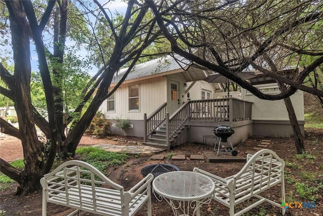 back of property with a wooden deck, stairs, and metal roof