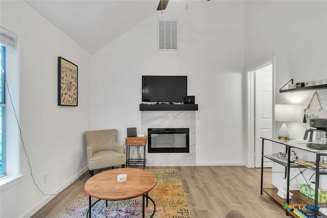 sitting room featuring wood finished floors, visible vents, a high end fireplace, and baseboards