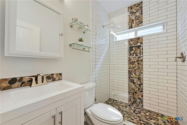 full bathroom with vanity, a tile shower, and toilet