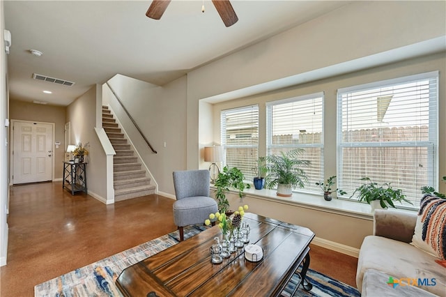 sitting room featuring visible vents, stairway, a ceiling fan, concrete flooring, and baseboards