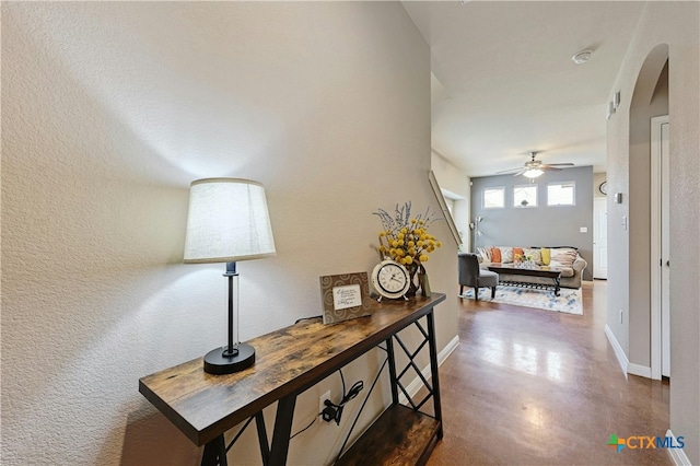 corridor with finished concrete flooring, baseboards, and arched walkways