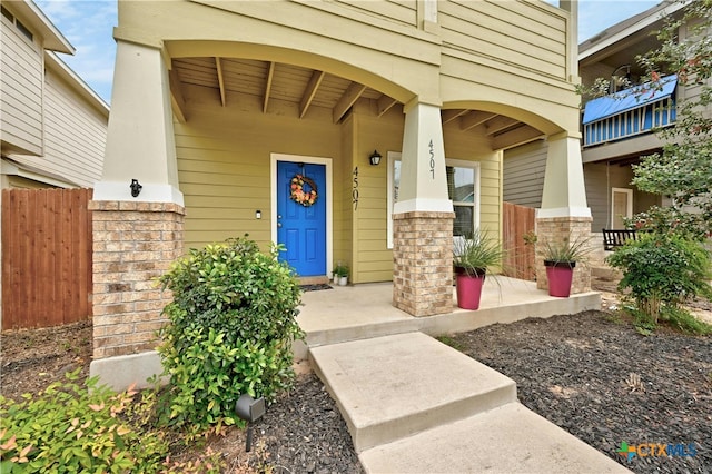 entrance to property with covered porch and fence