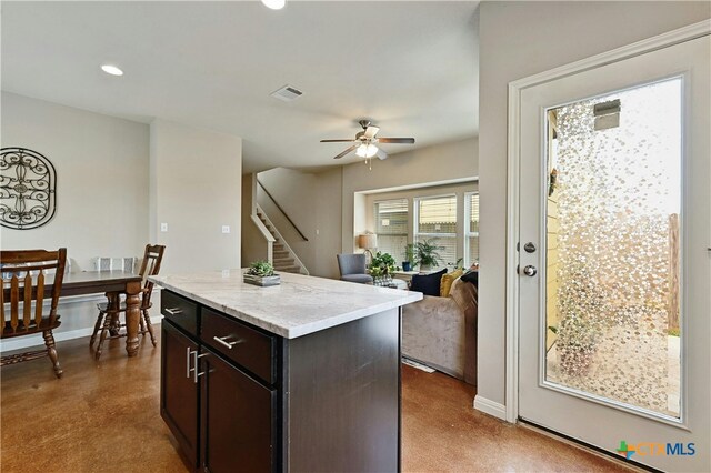 kitchen featuring baseboards, visible vents, a ceiling fan, open floor plan, and a center island