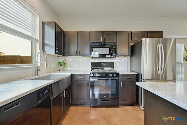 kitchen with a sink, black appliances, light stone counters, and backsplash