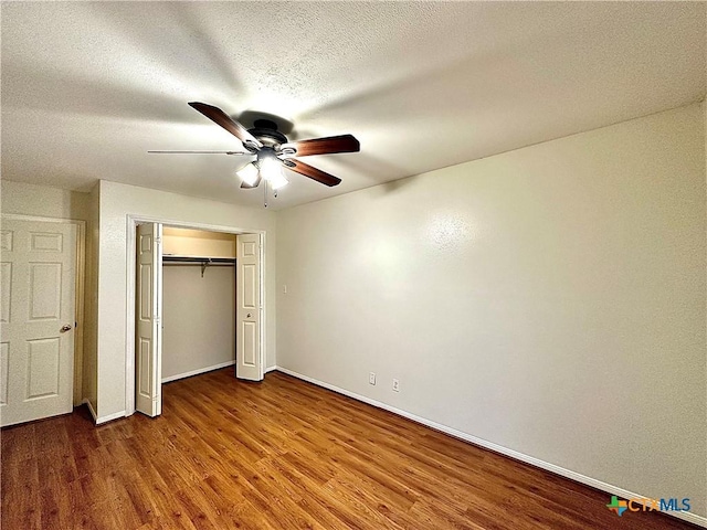 unfurnished bedroom with ceiling fan, a closet, a textured ceiling, and hardwood / wood-style flooring