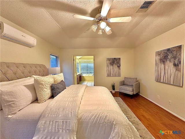110 Ashford Dr, Victoria, TX 77904 - bedroom featuring a wall mounted AC, a textured ceiling, wood finished floors, connected bathroom, and baseboards