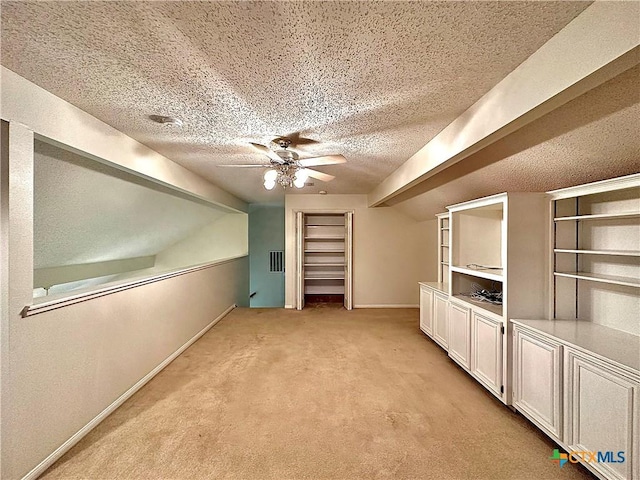 bonus room with light carpet, a textured ceiling, and ceiling fan