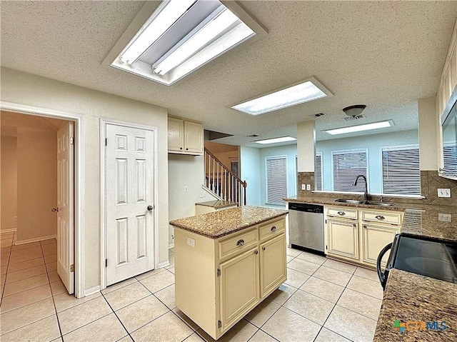 kitchen with cream cabinets, dishwasher, a center island, and sink