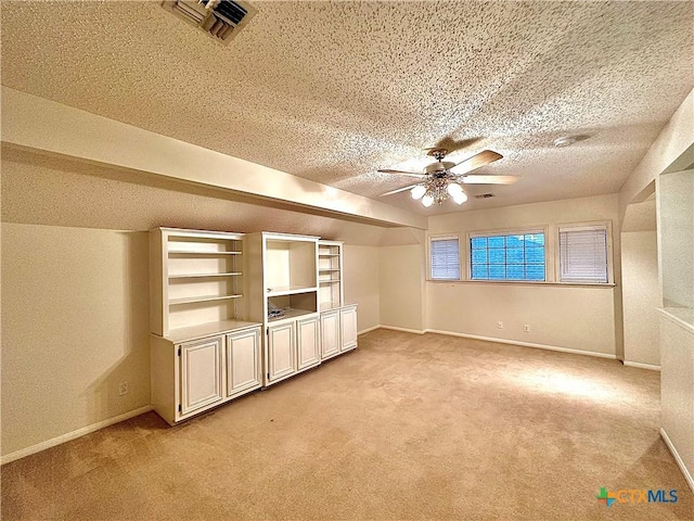 additional living space featuring light carpet, a textured ceiling, and ceiling fan