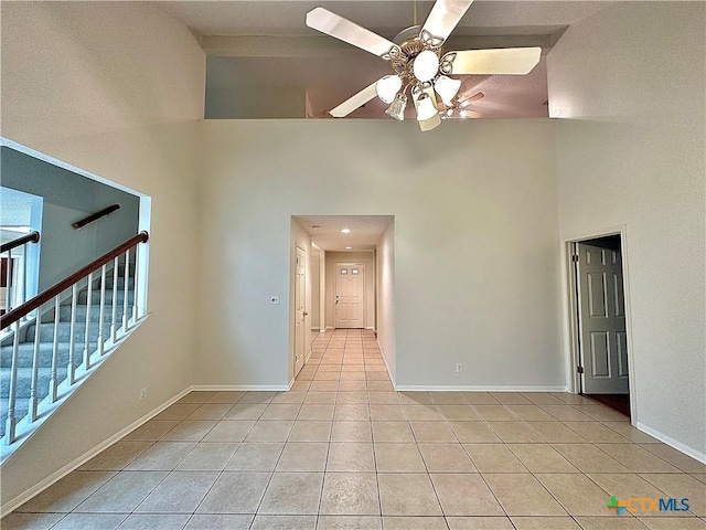 tiled spare room featuring ceiling fan and a high ceiling