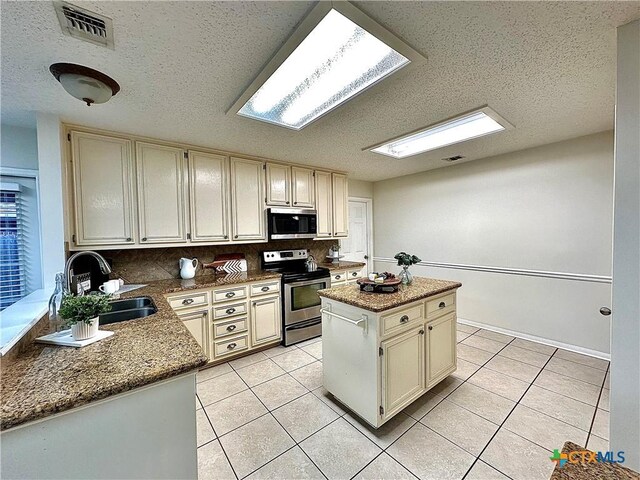 110 Ashford Dr, Victoria, TX 77904 - kitchen featuring visible vents, light tile patterned flooring, cream cabinetry, stainless steel appliances, and a sink