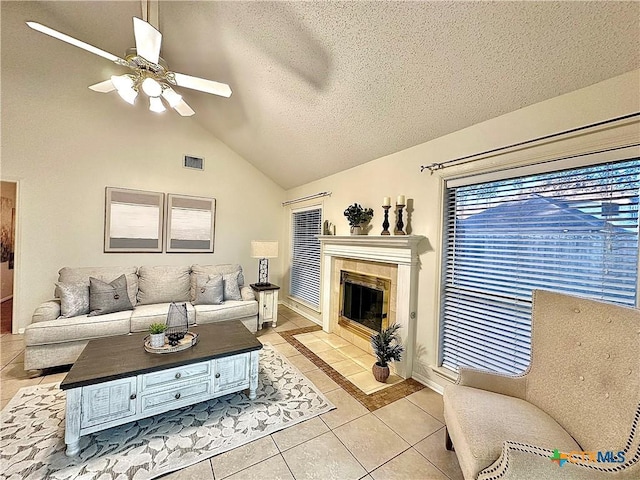110 Ashford Dr, Victoria, TX 77904 - living room with visible vents, ceiling fan, a tiled fireplace, vaulted ceiling, and light tile patterned flooring
