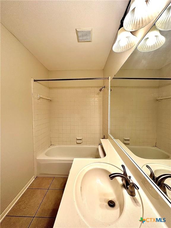 bathroom with tile patterned floors, vanity, and tiled shower / bath