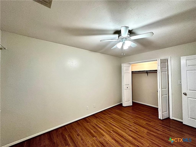 unfurnished bedroom featuring ceiling fan, a closet, dark wood-type flooring, and a textured ceiling