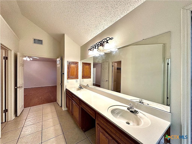 bathroom featuring ceiling fan, tile patterned flooring, a textured ceiling, vaulted ceiling, and vanity