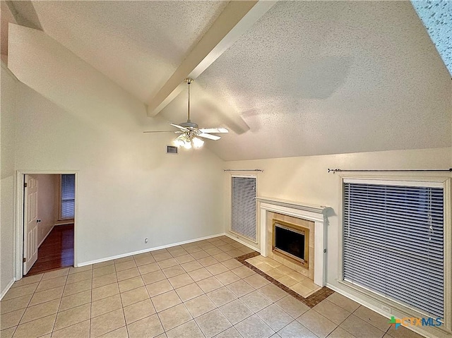 unfurnished living room featuring ceiling fan, lofted ceiling with beams, a textured ceiling, a tiled fireplace, and light tile patterned floors