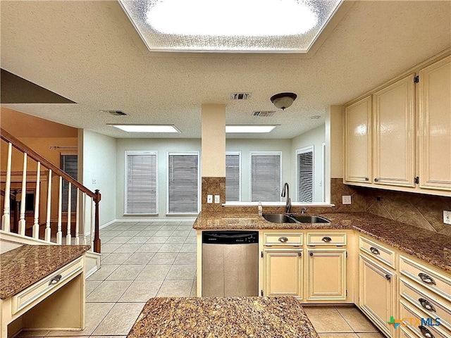 kitchen with sink, stainless steel dishwasher, light tile patterned floors, a textured ceiling, and cream cabinetry