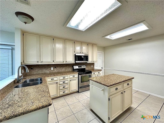 kitchen with a center island, cream cabinetry, stainless steel appliances, and sink