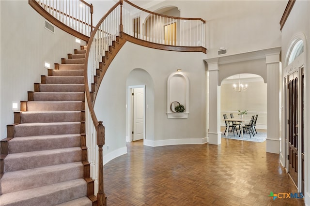 foyer entrance featuring a notable chandelier, dark parquet flooring, and a high ceiling