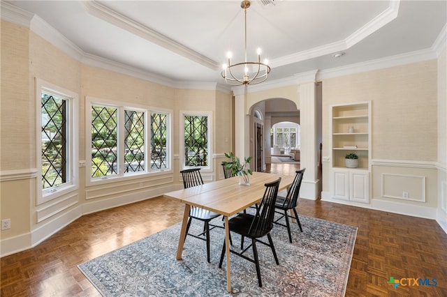 dining room featuring built in shelves, ornamental molding, a tray ceiling, dark parquet flooring, and a notable chandelier