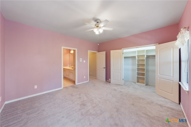 unfurnished bedroom featuring ceiling fan, connected bathroom, light carpet, and a closet