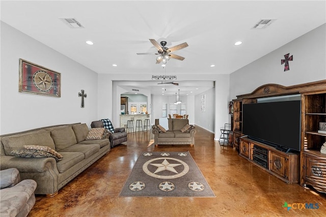 living room featuring concrete floors, visible vents, and a ceiling fan