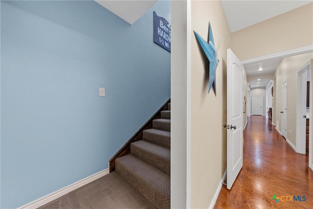 corridor featuring arched walkways, baseboards, stairs, and recessed lighting