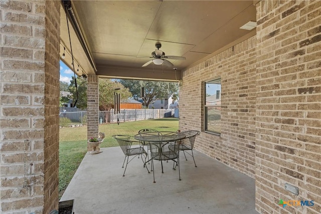 view of patio with fence, a ceiling fan, and outdoor dining area
