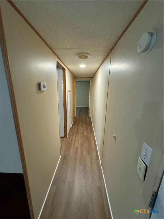 hallway featuring a textured ceiling and light hardwood / wood-style flooring