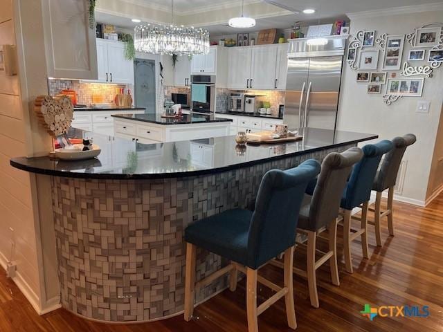 kitchen featuring crown molding, appliances with stainless steel finishes, a breakfast bar, and white cabinets