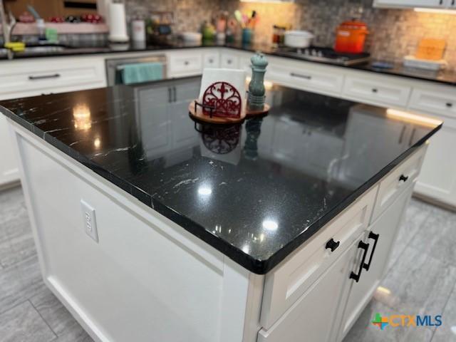 kitchen featuring backsplash, black gas stovetop, sink, and white cabinets