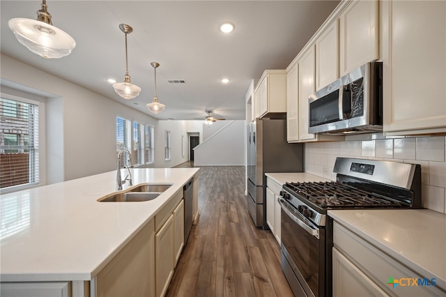 kitchen with backsplash, open floor plan, light countertops, appliances with stainless steel finishes, and a sink