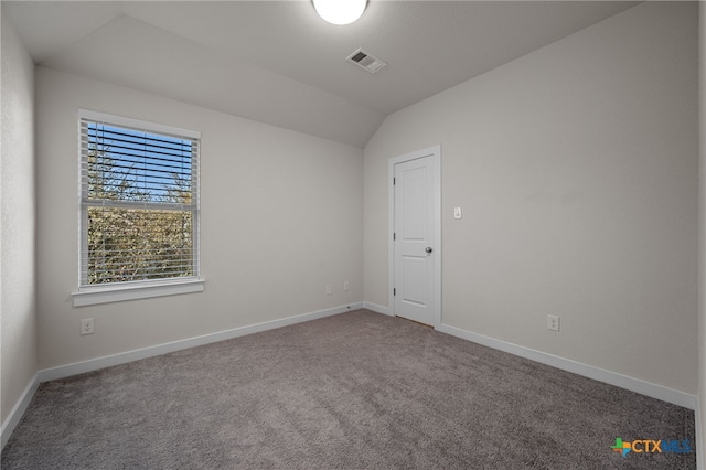 carpeted empty room featuring visible vents, baseboards, and vaulted ceiling