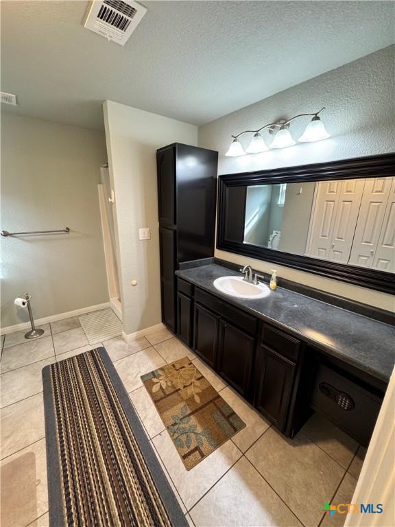 bathroom featuring tile patterned flooring, vanity, and a textured ceiling