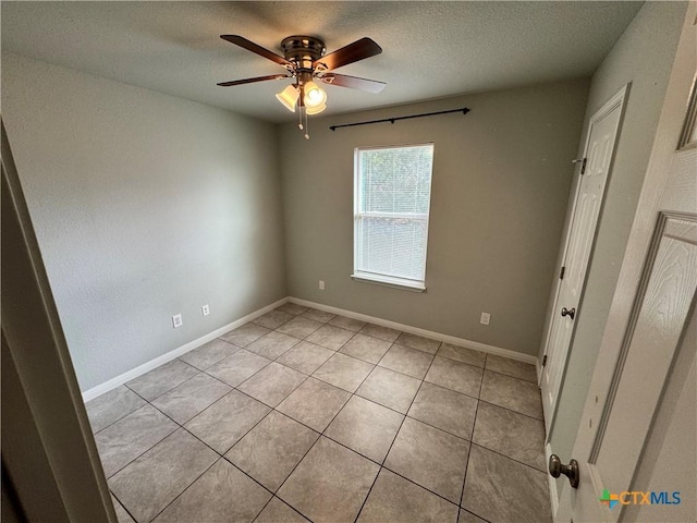 empty room featuring light tile patterned floors, a textured ceiling, and ceiling fan